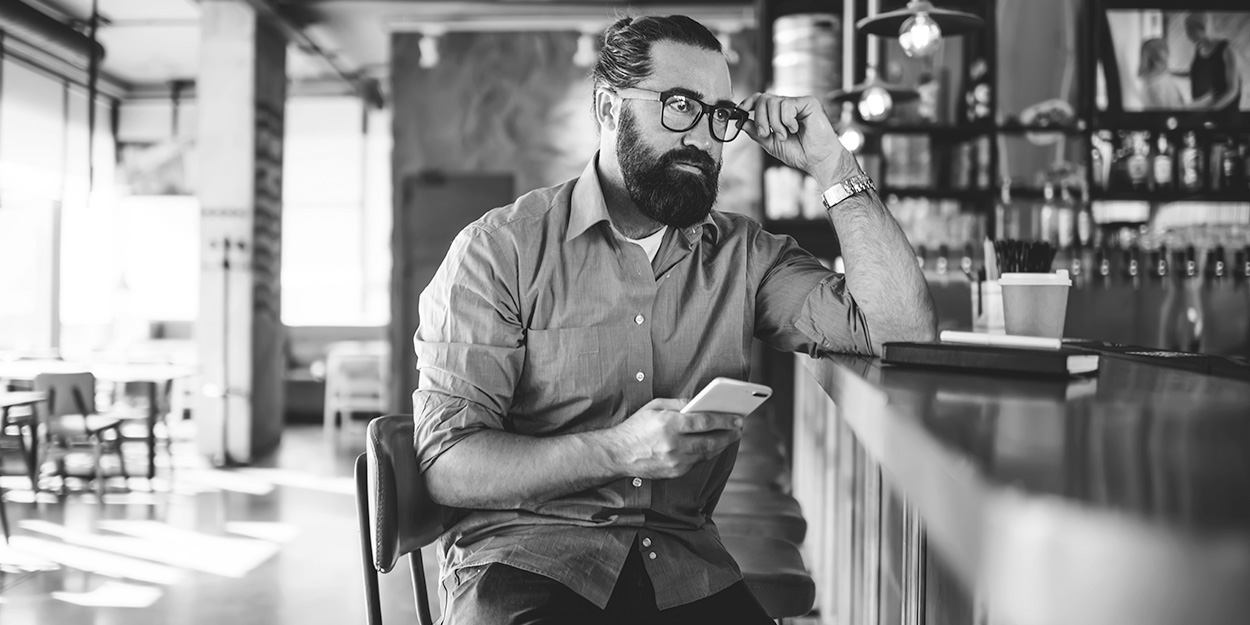 male business owner sitting at coffee shop bar looking concerned